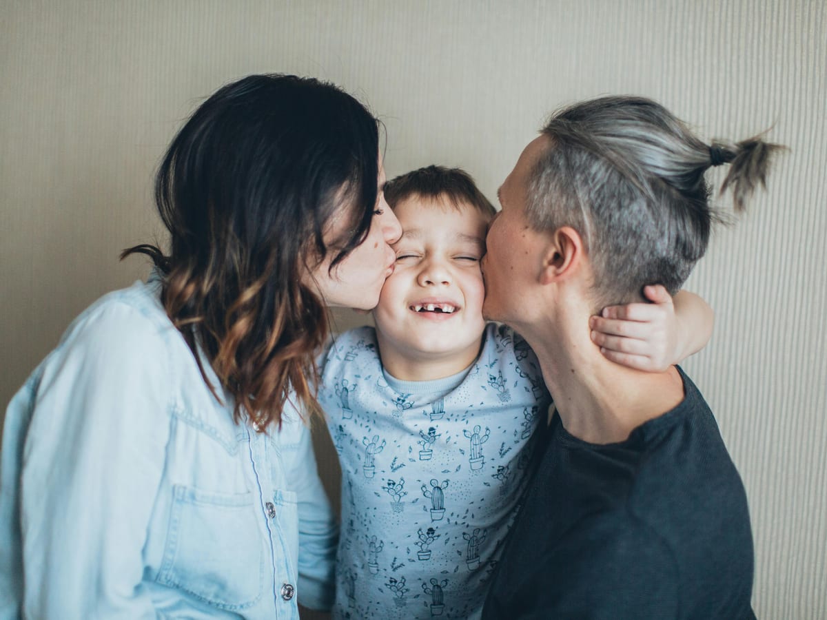Grandmother embracing her adult daughter and grandchildren in a bright living room